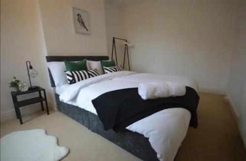 um quarto com uma cama grande com almofadas brancas e verdes em CONTRACTORDIGS with FREE parking - excellent road links em Nuneaton