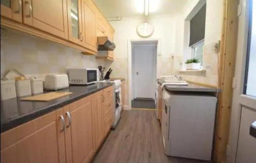 a kitchen with wooden cabinets and a counter top at CONTRACTORDIGS with FREE parking - excellent road links in Nuneaton