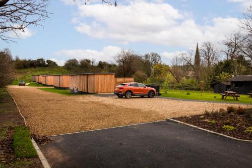 an orange car parked in a gravel parking lot at The Birdbox - Unique Cabin in Millport in Millport