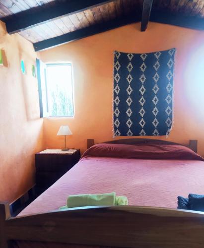 1 dormitorio con cama roja y almohada azul en La Ruca en El Hoyo