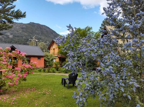 um banco sentado no quintal ao lado de uma árvore com flores roxas em Valle Puelo em Lago Puelo