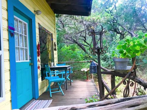 un porche de madera con una puerta azul y una mesa en The Mexico Cabin at Creekside Camp & Cabins, en Marble Falls