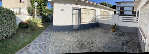 a house with a stone walkway next to a building at PH a 1 cuadra de la playa, 2 amb, patio y parrilla in Villa Gesell