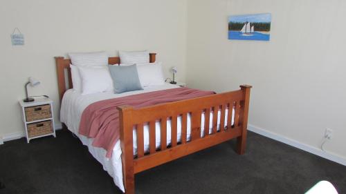 a bedroom with a wooden bed with white pillows at Self-contained Studio- 5 min to Waihi township, 10 min drive to Waihi beach in Waihi