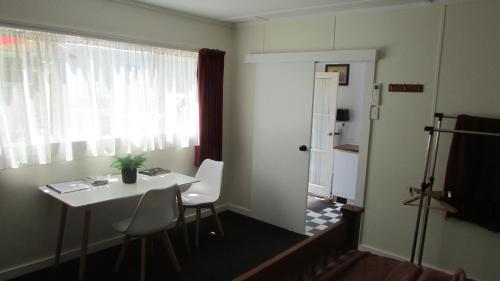 ein kleines Zimmer mit einem Tisch, Stühlen und einem Fenster in der Unterkunft Self-contained Studio- 5 min to Waihi township, 10 min drive to Waihi beach in Waihi