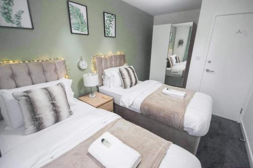 GF Apartment sleeps5 near Coventry City Centre with FREE SECURE gated parking في كوفينتري: غرفة نوم بسريرين ومرآة
