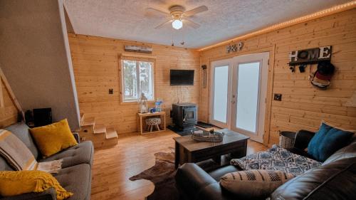 a living room with a couch and a tv in a room at Charming Blue Farmhouse Cabin in Duck Creek Village