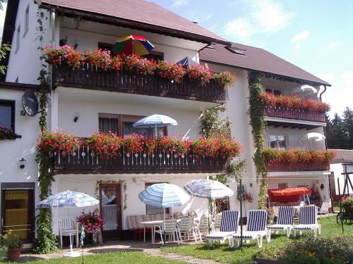 a building with chairs and umbrellas in front of it at Gästehaus Walter in Fichtelberg