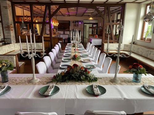 a long table with white tables and white chairs at Gasthaus Neue Mühle in Westhausen