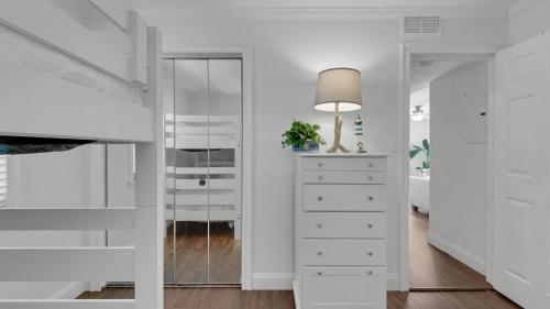 een witte slaapkamer met een dressoir en een spiegel bij Beachside Condo 1 in Santa Rosa Beach