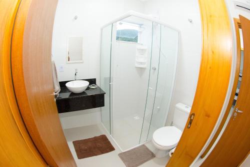 uma casa de banho com um chuveiro, um WC e um lavatório. em Apartamentos Sinhá em Penha