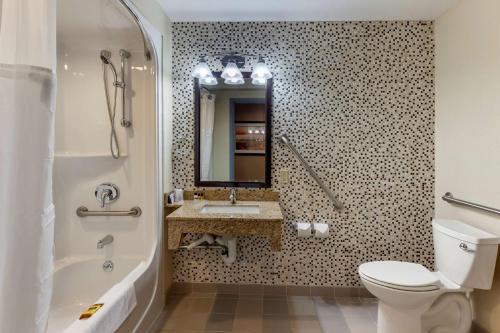 a bathroom with a toilet and a sink and a mirror at Best Western Plus Woodstock Inn & Suites in Woodstock