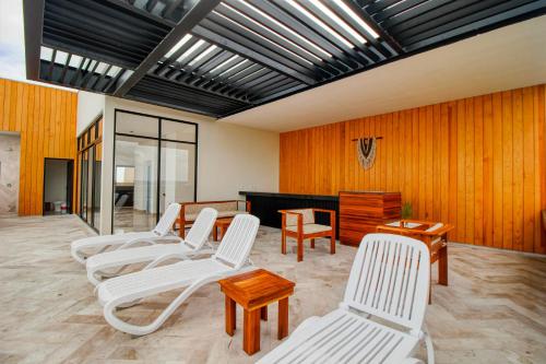 a room with white chairs and a wooden wall at Giada Towers A204 in Tulum