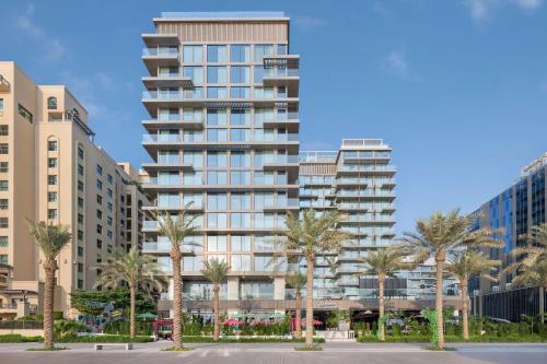 un grand bâtiment avec des palmiers devant lui dans l'établissement Radisson Beach Resort Palm Jumeirah, à Dubaï