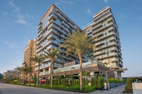 a tall building with palm trees in front of it at Radisson Beach Resort Palm Jumeirah in Dubai