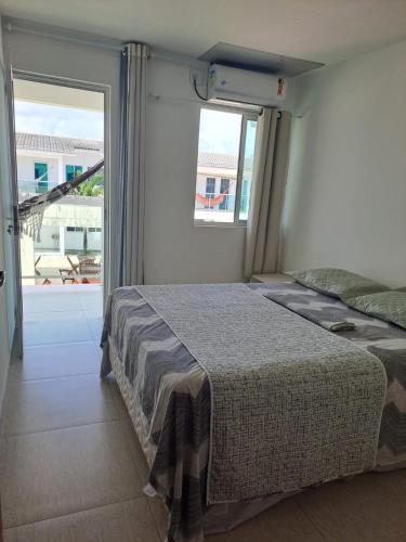 a bedroom with a bed and a large window at Bangalô/Dúplex Jacumã Conde in Jacumã