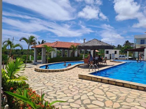 a pool at a resort with a table and chairs at Apartamento/Flat em Jacumã in Conde