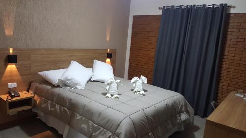 a hotel room with a bed with two robots on it at Hotel Garnier in Campos do Jordão