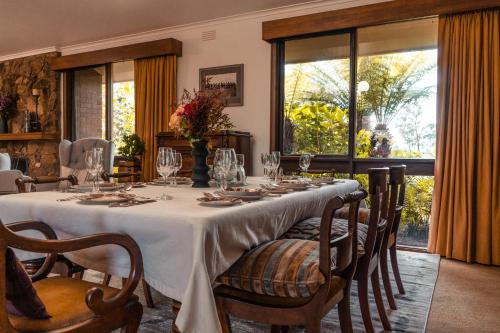 uma sala de jantar com uma mesa longa com cadeiras e copos em Boutique LUXE HomeStay Stunning VIEWS ! Villa em Orbost