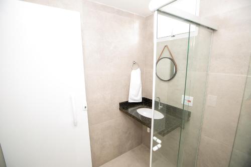 a bathroom with a sink and a glass shower at Jahu Center Plaza Flats in Jaú