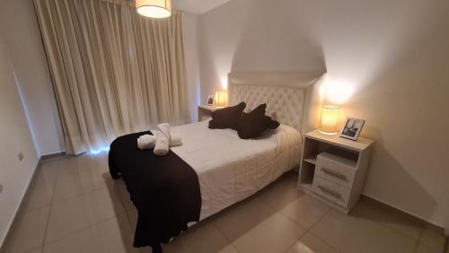 1 dormitorio con 1 cama con almohadas blancas y negras en HOUSING CORDOBA - Carlos Paz Opera en Villa Carlos Paz