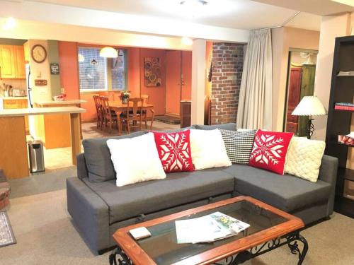 uma sala de estar com um sofá cinzento com almofadas vermelhas e brancas em Large Suite Fairfield Heritage Manor, Free Parking em Victoria