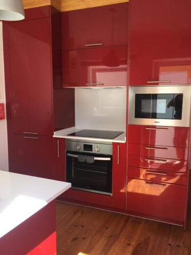 a red kitchen with a stove and a microwave at Covil's Haus in Peniche