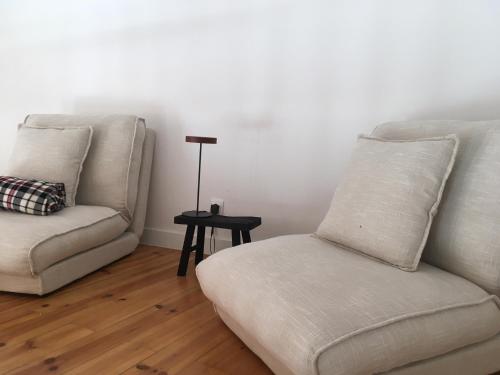 a living room with two white couches and a side table at Covil's Haus in Peniche