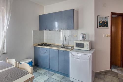 a kitchen with blue cabinets and a sink and a microwave at Apartments with a parking space Pirovac, Sibenik - 15320 in Pirovac