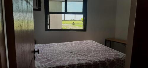 a room with a window and a bed with a table at Chalé Pé na Areia em Rio das Ostras in Rio das Ostras