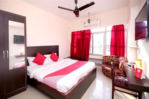 a bedroom with a bed and a desk and red curtains at OYO Hotel Dwarika Inn in Jabalpur