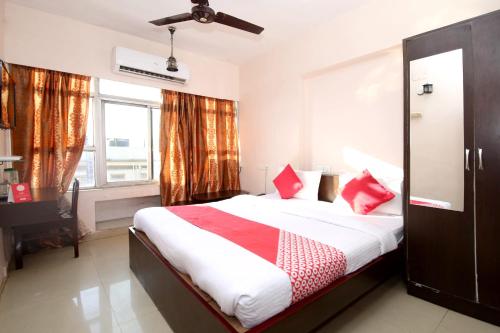 1 dormitorio con 1 cama grande con almohadas rojas en OYO Hotel Dwarika Inn, en Jabalpur