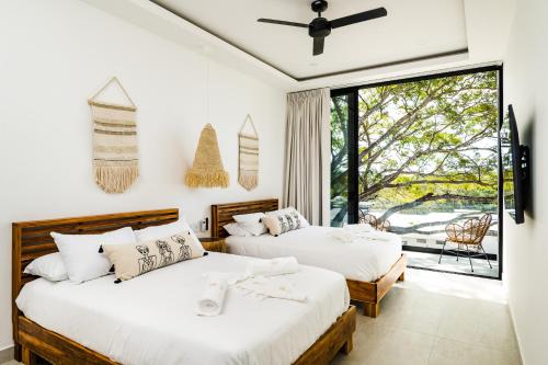 two beds in a room with a window at The mVilla with Exclusive Beach Club Access in Tamarindo