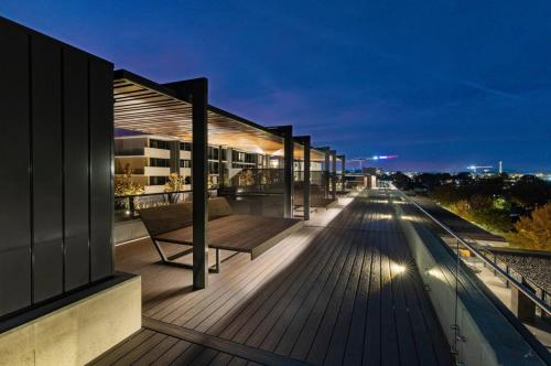 a building with a bench on a deck at night at Mulberry 2BR-2BA Rooftop Pool, BBQ, WiFi & Netflix - Central Location in Canberra