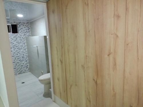 baño con puerta de madera a un aseo en Roatán, en Gaira