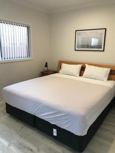 a large bed in a bedroom with a white bedspread at Fragrant Home-68A Brand New 2 rooms House with beautiful private garden and entrance,5G wifi in Doonside