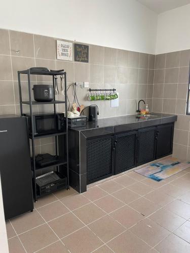 a kitchen with a black counter with a sink and a counter at Anas House in Tanjung Rambutan