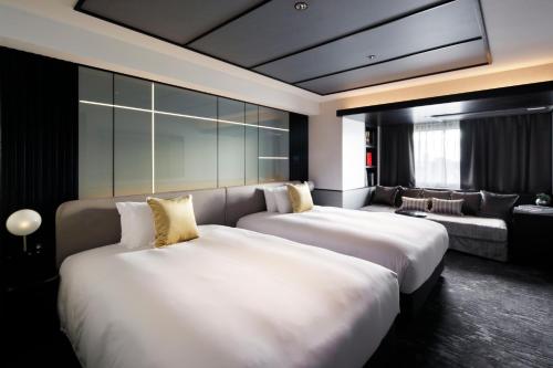 a hotel room with two beds and a couch at Cross Hotel Osaka in Osaka