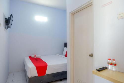 a small room with a bed and a door at RedDoorz near Puri Anjasmoro Area Semarang in Semarang