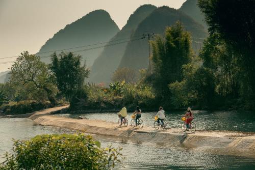 a group of people riding bikes along a river at The Apsara Lodge in Yangshuo