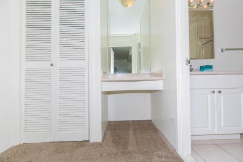 La salle de bains est pourvue de placards blancs, d'un lavabo et d'un miroir. dans l'établissement Ilikai Marina 380 Yacht Harbor View 1BR, à Honolulu