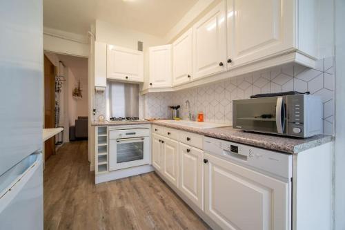 une cuisine blanche avec des armoires blanches et un micro-ondes dans l'établissement Fully equipped apartment balcony sleeps 7 wifi, à Marseille