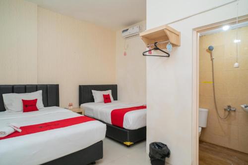 a hotel room with two beds and a shower at RedDoorz near Flyover Arjosari Malang in Malang