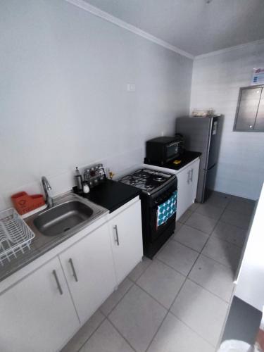 a small kitchen with a sink and a stove at Departamento sector florida in La Serena