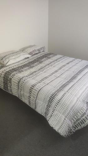 a bed with a black and white striped comforter at Departamento sector florida in La Serena
