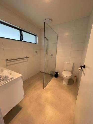 a bathroom with a toilet and a glass shower at Inverloch Motel in Inverloch