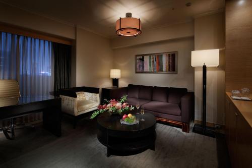 a living room with a couch and a piano at Grand Prince Hotel Shin Takanawa in Tokyo