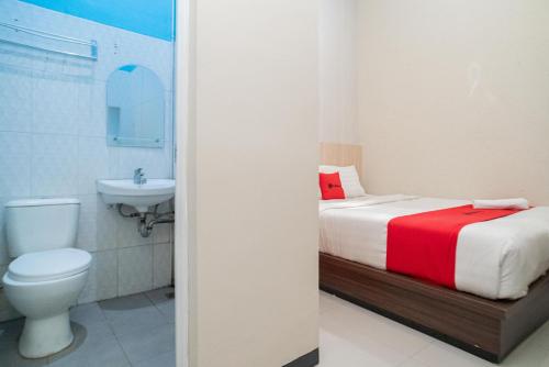 y baño con cama, aseo y lavamanos. en RedDoorz near Matahari Singosaren Solo, en Solo