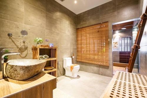 a bathroom with a large stone sink and a toilet at Samaya Luxury Villa - Melaka in Kelebang Besar