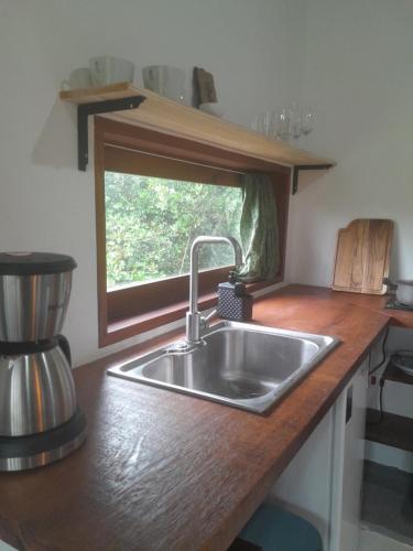 un comptoir de cuisine avec un évier et une fenêtre dans l'établissement Hakuna Studios Barra do Sahy, à Barra do Sahy